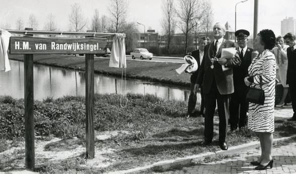 Gorinchem: Burgemeester Ridder van Rappard is in gedachten bij de in Gorinchem geboren Henk van Randwijk. "Hoe was het ook weer?" Hendrik Mattheus van Randwijk was een journalist, schrijver en dichter, maar bovenal bekend als verzetsman. Hij was één van de oprichters van Vrij Nederland en tijdens en na de Tweede Wereldoorlog hoofdredacteur. We zien op de foto de onthulling in 1970 van het naambord van de H.M. van Randwijksingel. Dit gebeurde door mevrouw Ada van Randwijk, zelf ook betrokken bij Vrij Nederland tijdens de oorlog. Het initiatief voor dit huldeblijk lag bij de heer G.J. Kroef, de nestor van de Gorcumse gemeenteraad. Op de achtergrond zien we de straat Stalkaarsen met geheel rechts de Torenflat. Tussen de burgemeester en mevrouw van Randwijk staat de hulpbode H. van Scherpenzeel. Indrukwekkend zijn de dichtregels van Henk van Randwijk die staan op het monument in het Weteringplantsoen in Amsterdam: Een volk dat voor tirannen zwicht, zal meer dan lijf en goed verliezen, dan dooft het licht.