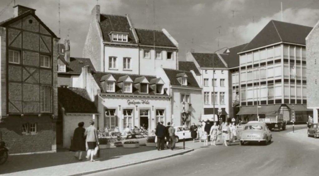 We staan omstreeks 1961 op het Bat en kijken naar de Vissersmaas en de ingang van de Maastrichter Smedenstraat. Het pand rechts op de foto is in 1960 gebouwd, naar ontwerp van Gerard Snelder. De foto is veel jonger dan verondersteld wordt. Het vakwerkhuis