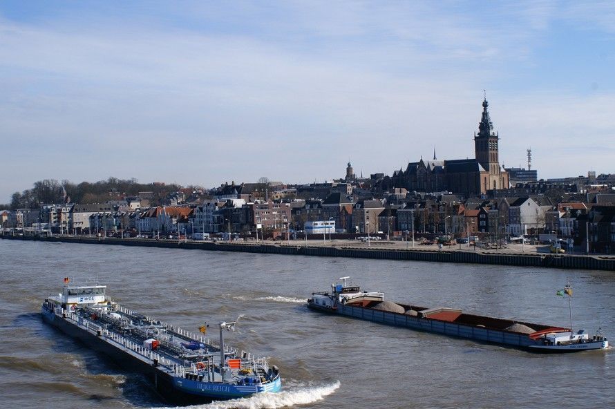 Schepen op de Waal varen in de daalvaart voorbij de Nijmeegse Waalkade