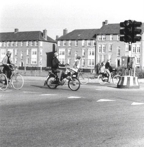 Nijmegen 1974: Zicht vanaf het kruispunt Dennenstraat en de Paul Krugerstraat met op de achtergrond de appartementen van de Hendrik de Keijzerstraat; in het midden een passerende Puch. Een veel voorkomend vervoersmiddel in die jaren.