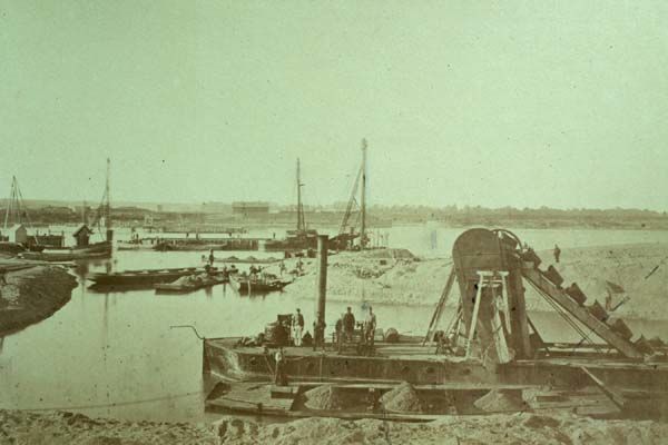 Nijmegen: Aanleg van de spoorbrug over de Waal, gezien vanaf de Lentse oever. Foto uit circa 1875.