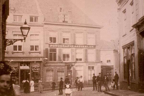 Nijmegen: Winkel in fotografie artikelen van C.A.P. Ivens op de hoek Lange Brouwerstraat en de Priemstraat, gezien vanuit de Ganzenheuvel. Foto uit circa 1890.