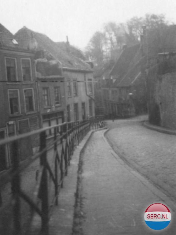 Nijmegen: De Vleeshouwerstraat in 1939 gezien in de richting van de Lindenberg. Rechts bij de lantaarn aan de muur de omhooglopende Strikstraat. Links achter het hek de Steenstraat.