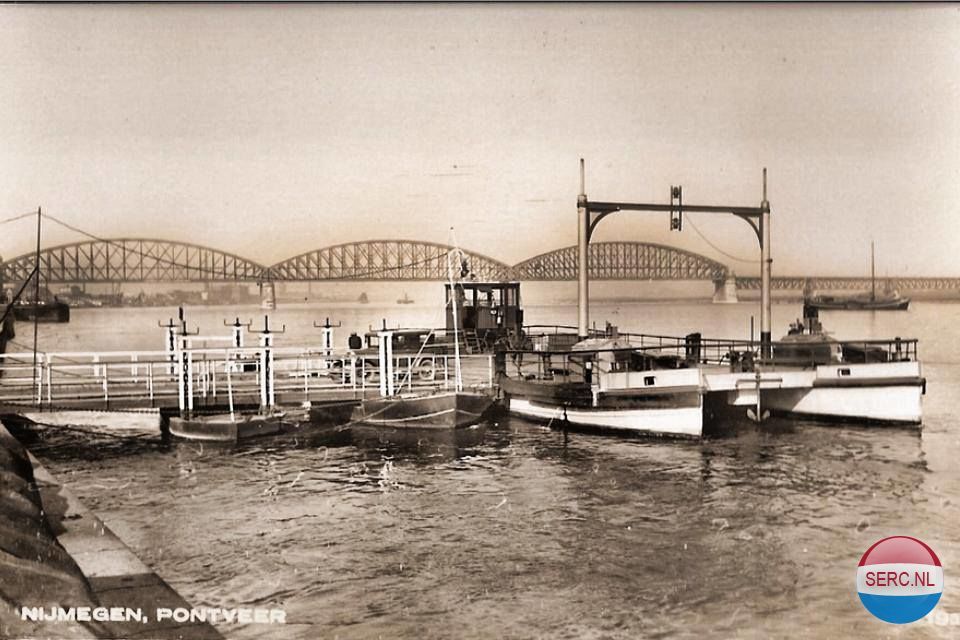 Nijmegen: Een oldtimer (toen uiteraard nog een vrij nieuwe automobiel) verlaat de oude veerpont over de Waal. Op de achtergrond de oude spoorbrug omstreeks 1933