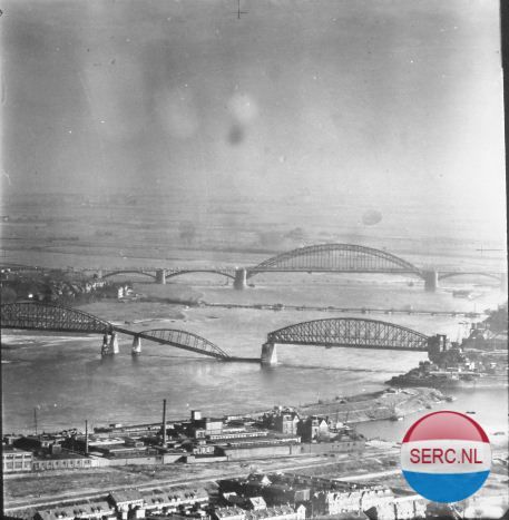 Nijmegen: Vanwege de schade aan beide bruggen over de Waal besloten de geallieerden ook een Baileybrug te bouwen die op deze foto (tussen de beide vaste bruggen) goed te zien is. (1944)