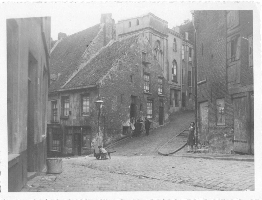 De omhooglopende Strikstraat in 1930 gezien vanuit de Steenstraat. Rechts en Links de Vleeshouwerstraat. Bovenaan de foto zien we nog een deel van het Kasteel Bat-Ouwe-Zate (kasteel Hallo).