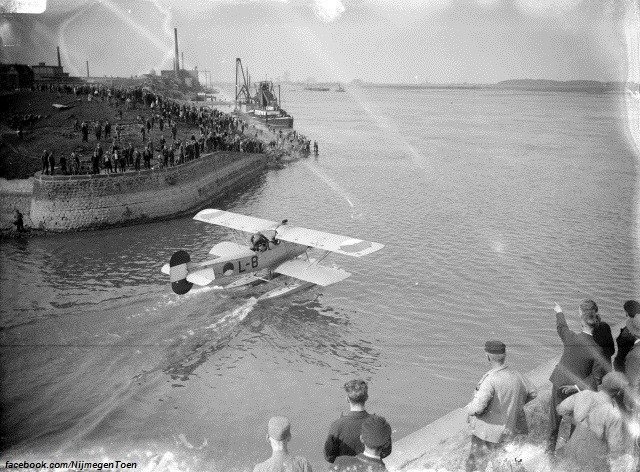Een watervliegtuig dat Nijmegen bezocht heeft, verlaat in 1937 de Waalhaven nabij de Spoorbrug om vanaf de Waal op te stijgen. De Nijmeegse bevolking is uitgelopen om het tafereel te aanschouwen.