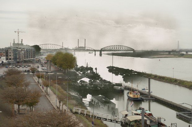 Nijmegen. De Waalkade is 100 jaar lang al grotendeels hetzelfde. Het grootste verschil met nu is de oude spoorbrug uit 1879. Op deze foto hebben de mensen van ''aswespeak'' een oude foto bewerkt met een recente foto zodat we dus 2 tijdsbeelden elkaar zien overlappen.