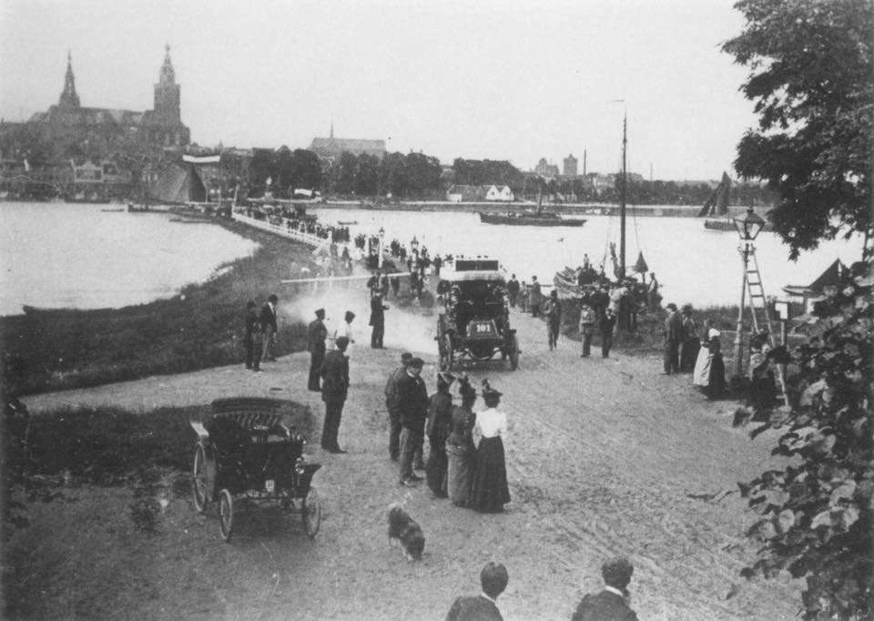 De Waalkade in Lent omstreeks 1898. Derde dag van de automobielentocht Parijs-Amsterdam-Parijs, die van 7 juli t/m 13 juli 1898 gehouden werd, ter kennismaking met het nieuwe voertuig en in Nederland ter opsiering van de eveneens in juli 1898 opgerichte NAC (Ned. Automobielen Club, tegenwoordig de Koninklijke KNAC), van wie de Nijmegenaar Michael Aertnijs één van de drie oprichters was. Hier de overtocht van de Waal en start van de etappe Nijmegen-Amsterdam. In het midden de schipbrug met op de achtergrond de St. Augustinuskerk en de St. Stevenskerk.