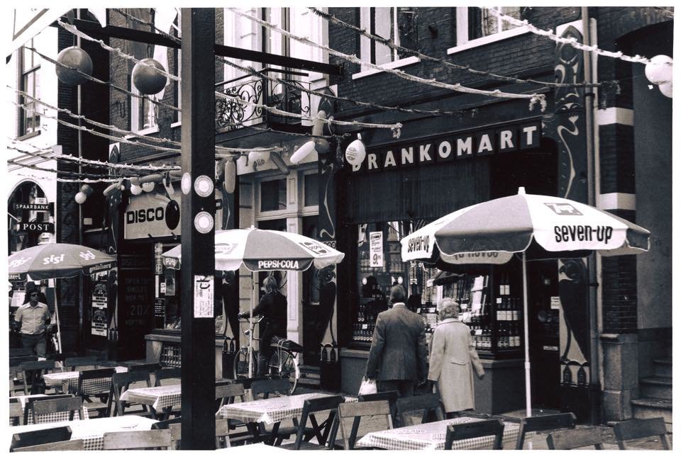 De Lange Hezelstraat halverwege de jaren '70. Toen nog Hezelstraat Promenade geheten. We kijken tegen de slijterij 'Drankomart' aan. Links naast de slijterij de 'Disco Shop'.