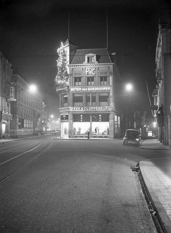 Peek en Cloppenburg bij avond in 1937 op de foto gezet vanuit de Lange Burchtstraat met links de Korte BurchtstraatLinks de Korte Burchtstraat, rechts van P&C de Platenmakersstraat